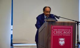 Michael Dawson, a Black man in a suit, standing in front of a UChicago podium speaking